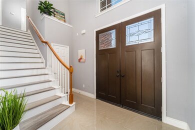 Wood double doors open to a 20-ft ceiling and a gr