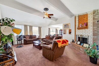 Carpeted living area featuring a brick fireplace, plenty of natural light, and ceiling fan