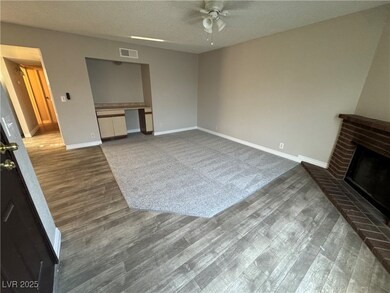 Unfurnished living room with dark wood-type flooring, a textured ceiling, built in desk, a fireplace, and ceiling fan