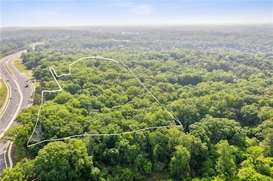 Aerial overview of property's location with a heavily wooded area, property parcel outlined, and a highway