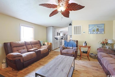 Living room with light wood-style flooring, ceiling fan, and a textured ceiling