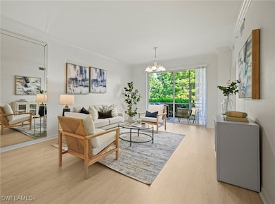 Living room with light wood-style floors, crown molding, and a chandelier