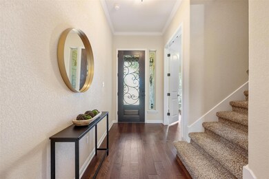 Foyer entrance with ornamental molding, dark wood finished floors, a textured wall, and stairs