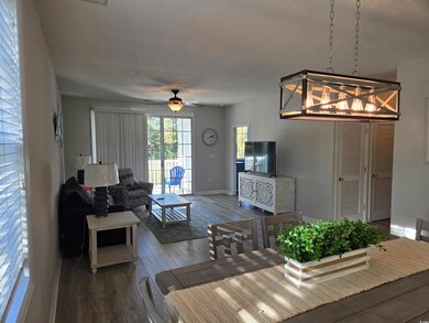 Living area with wood-type flooring, a textured ceiling, a ceiling fan, and a chandelier