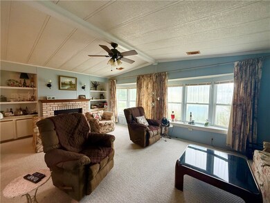 Carpeted living area featuring built in shelves, a brick fireplace, and ceiling fan