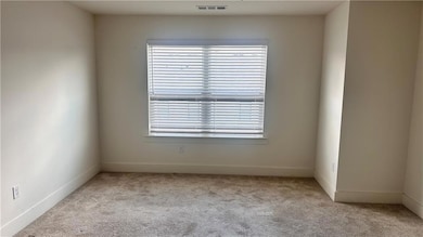 Spare room with light colored carpet and baseboards