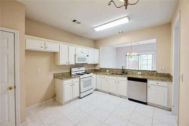 Kitchen with white appliances, a chandelier, a sin