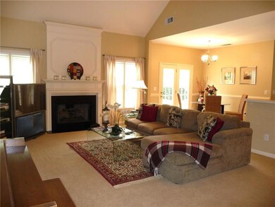 Living area with a large fireplace, light carpet, a chandelier, and vaulted ceiling