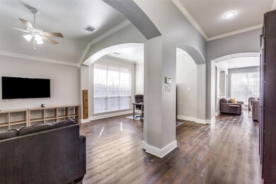 Living room with vaulted ceiling, dark hardwood / wood-style flooring, ornamental molding, and ceiling fan
