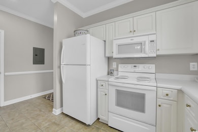 Kitchen featuring white appliances, electric panel, light countertops, white cabinetry, and crown molding