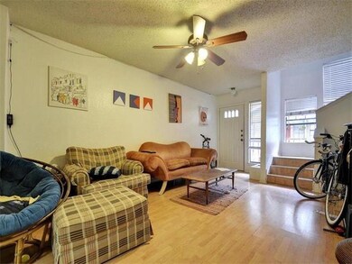 Living area featuring a textured ceiling, light wood-type flooring, and a ceiling fan