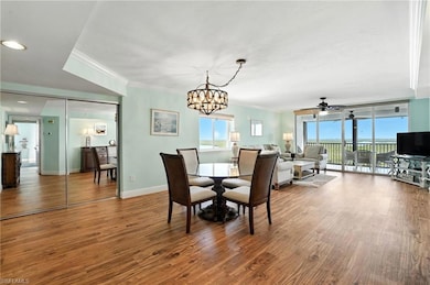 Dining room - Living room featuring ornamental molding, ceiling fan, wood finished floors, and a chandelier - Virtually Edited Image