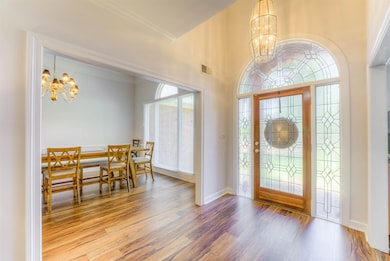 Entrance foyer with a chandelier, wood finished floors, crown molding, and baseboards