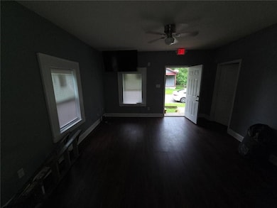 Empty room featuring a ceiling fan and dark wood-type flooring