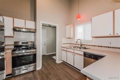 Kitchen with decorative backsplash, white cabinetry, stainless steel appliances, light countertops, and a towering ceiling