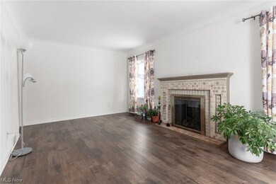 Living room featuring dark hardwood / wood-style floors, a brick fireplace, and crown molding