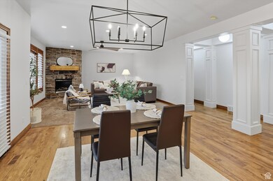 Dining space featuring light wood-style floors, a stone fireplace, recessed lighting, and a chandelier
