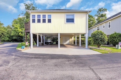 Coastal inspired home featuring a carport, stairs, and asphalt driveway