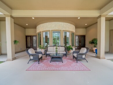 Texas Sized front porch with a back drop of windows showcasing the grand foyer of this estate.