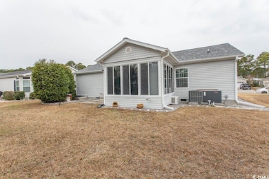 Back of house with a lawn, a sunroom, and cooling 