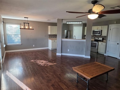 Unfurnished living room featuring dark wood-type flooring, a chandelier, and ceiling fan