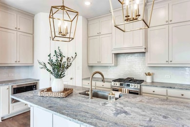 Kitchen with decorative backsplash, a chandelier, light stone countertops, and stainless steel range with gas cooktop