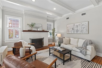 Living room boasts gleaming heart pine flooring, cozy wood fireplace & plantation shutters.