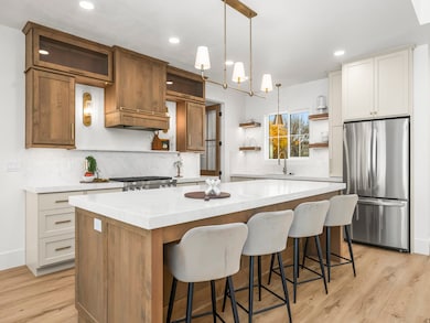 Kitchen with open shelves, brown cabinets, pendant lighting, freestanding refrigerator, and a center island