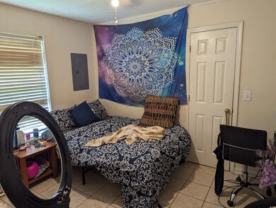 Bedroom featuring electric panel, light tile patterned floors, and a textured ceiling