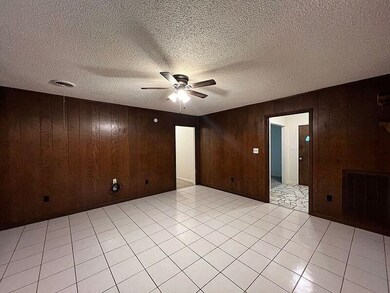 Tiled spare room featuring ceiling fan, a textured