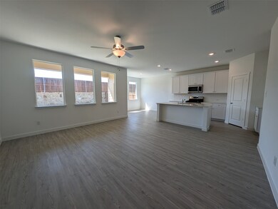 Kitchen featuring open floor plan, white cabinetry, an island with sink, dark wood-style floors, and stainless steel appliances