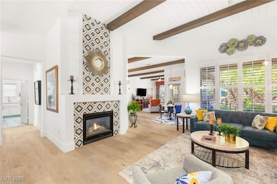Living area with light wood-type flooring, beamed