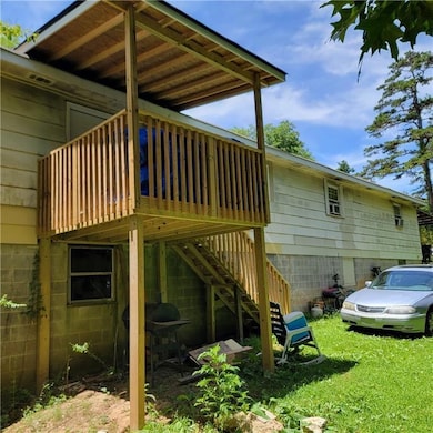 View of side of home featuring stairway, a deck, and a lawn