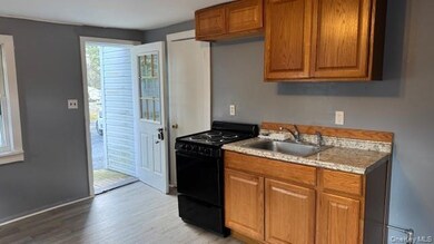 Kitchen with brown cabinets, black range with electric cooktop, light countertops, and light wood-style floors
