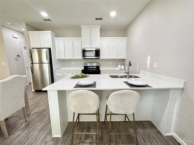 Kitchen with stainless steel appliances, white cabinets, a breakfast bar area, dark wood-type flooring, and a peninsula