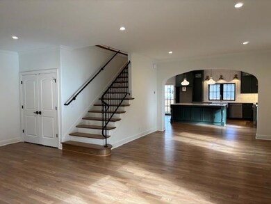 Unfurnished living room with recessed lighting, dark wood-style floors, ornamental molding, stairs, and arched walkways