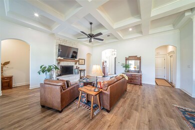 Living room featuring ceiling fan, a fireplace, coffered ceiling, light hardwood / wood-style floors, and beam ceiling
