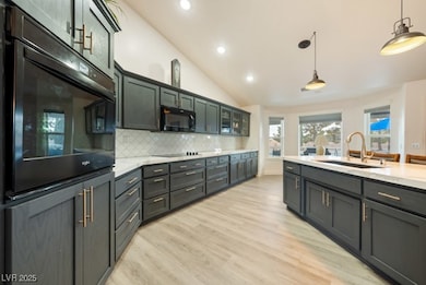 Kitchen with black appliances, a sink, light wood