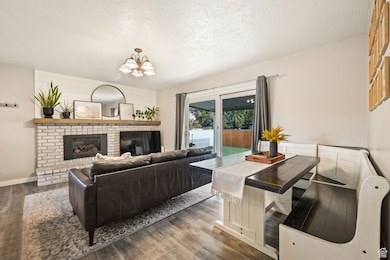 Living room with a textured ceiling, a fireplace, wood finished floors, and a chandelier