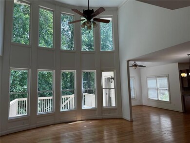 Doorway featuring a ceiling fan, a towering ceiling, wood finished floors, baseboards, and a chandelier