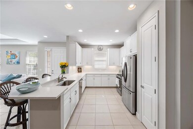 Kitchen with a kitchen bar, a peninsula, white cabinets, stainless steel appliances, and light tile patterned floors