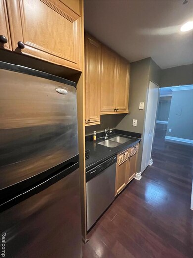 Kitchen with fridge, dark wood-style flooring, dishwasher, and light brown cabinetry