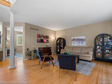 Living room featuring decorative columns and light wood-style flooring