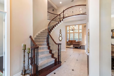 Tiled foyer entrance featuring baseboards, a high ceiling, stairway, and a chandelier