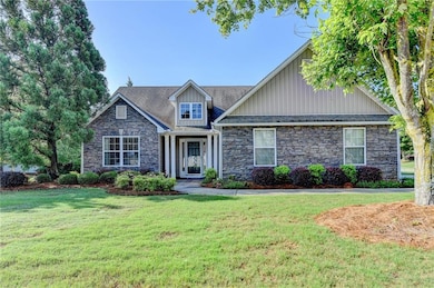 Craftsman-style house with stone siding, a front yard, and board and batten siding