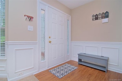 Foyer with laminate floors, chair rail, picture-frame wainscoting.  Side lights on front door.