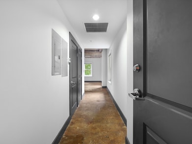 Hall with unfinished concrete flooring and electric panel