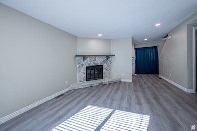 Unfurnished living room with wood finished floors, a fireplace, and recessed lighting