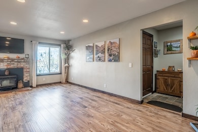 Unfurnished living room featuring laminate flooring, wood stove, and recessed lighting