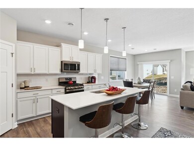 One-level living with dream kitchen featuring an oversized island, quartz countertops, tile backsplash, slate finish appliance package including refrigerator and walk-in pantry. Photo of model home, colors and finishes will vary.